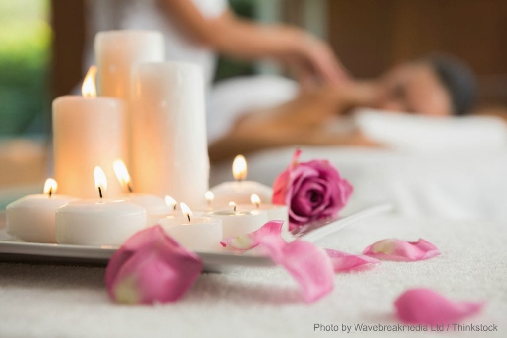 Candles and rose petals on massage table at the health spa